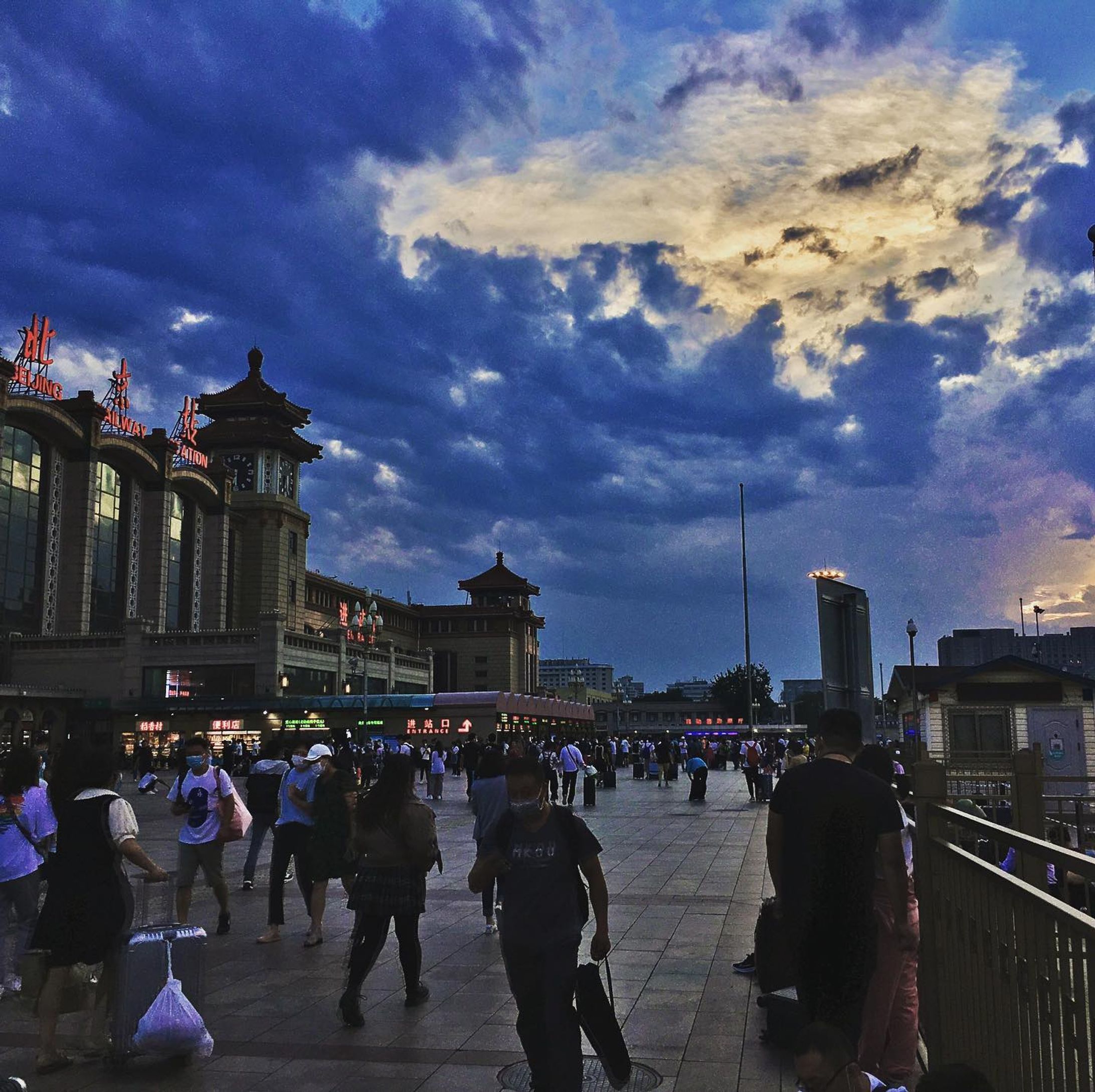 Beijing Railway Station under a bright, orange sun scattered by billowing, blue clouds.-1